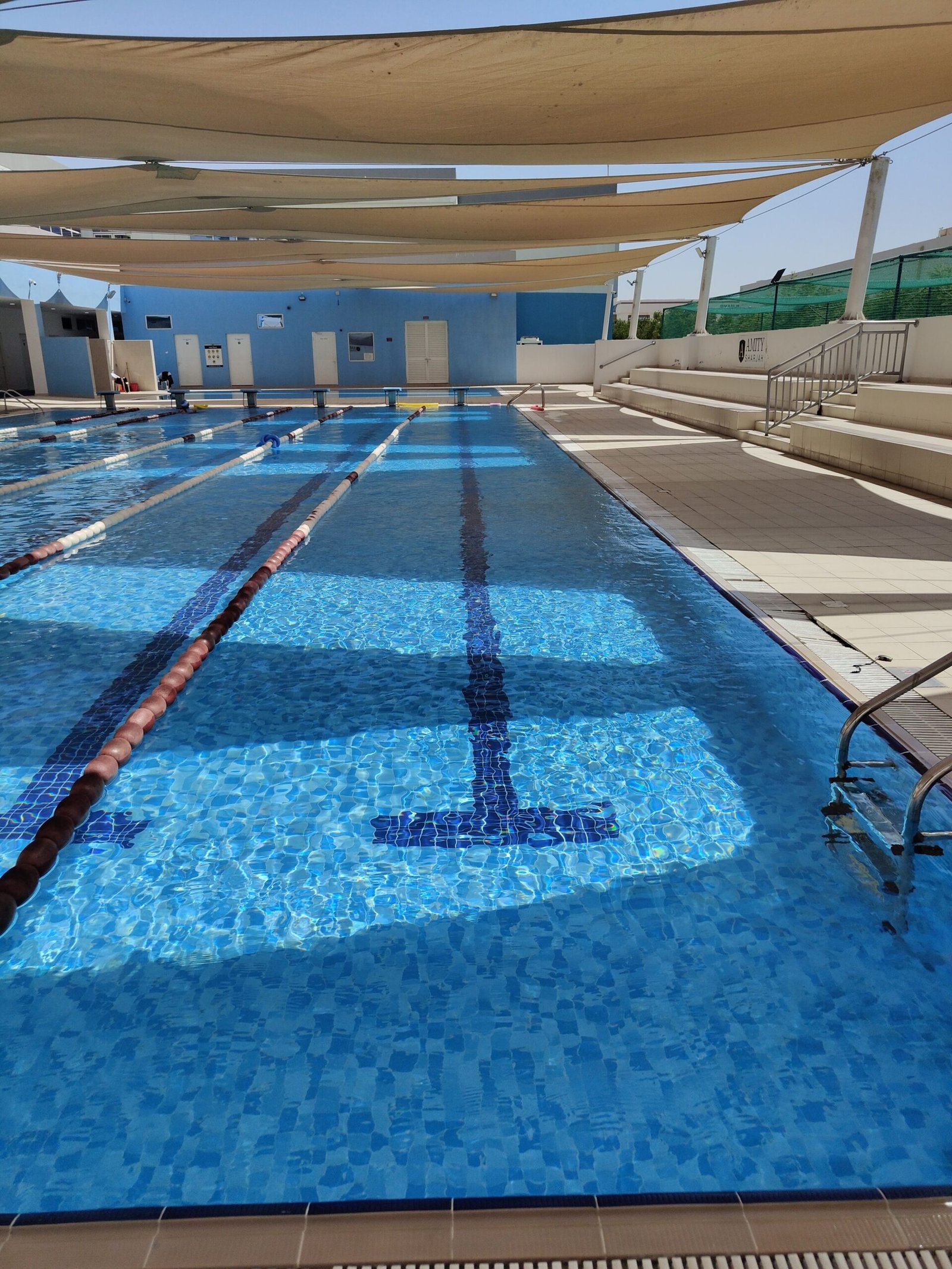 Shaded outdoor swimming pool with lanes, perfect for training or recreation, in the UAE.